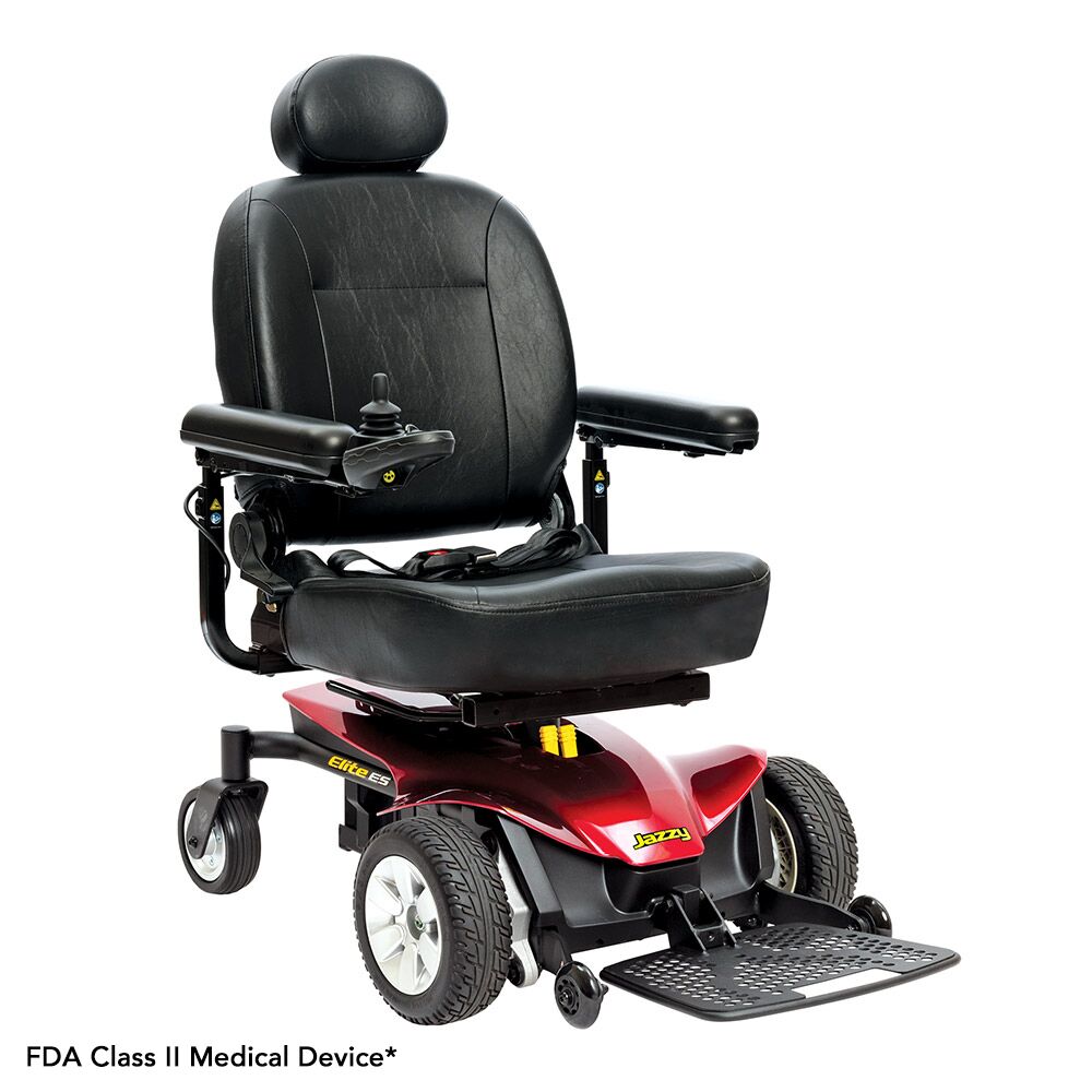 The Jazzy Elite ES Power Wheelchair is a black and red electric wheelchair featuring a padded seat, armrests, footrest, control joystick, four wheels, and an FDA Class II Medical Device label.