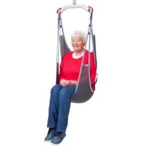 An elderly woman in a red sweater and jeans sits comfortably in a Molift EvoSling Ampu MediumBack Net Padded chair lift against a pristine white background.